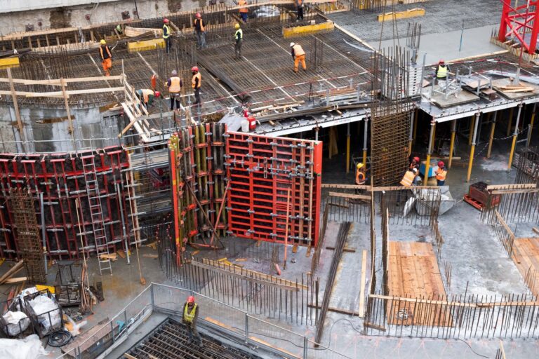 Cum alegi constructorul potrivit pentru sediul sau hala firmei Șantier de construcție al unei hale industriale cu structură metalică și macara în fundal