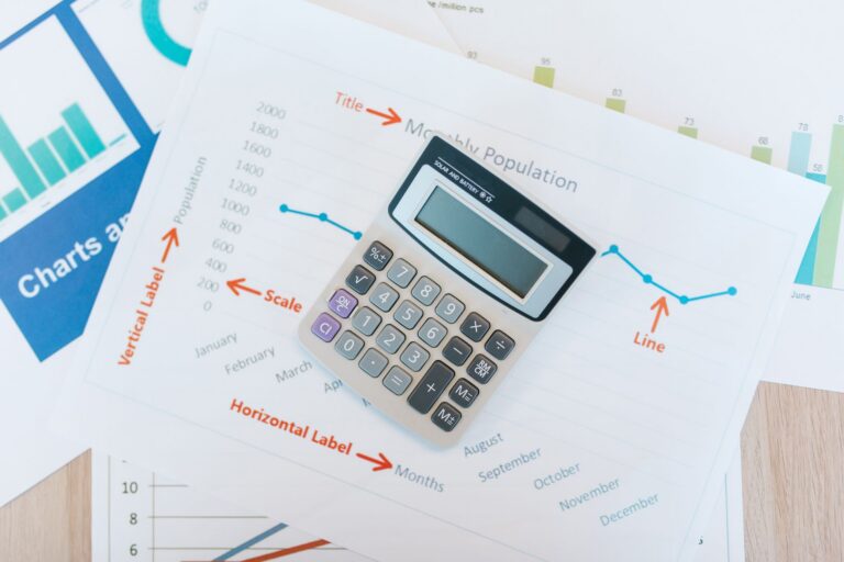 Finanțele firmei explicate pe înțelesul antreprenorului Rapoarte financiare tipărite, un calculator și un pix pe biroul unui antreprenor
